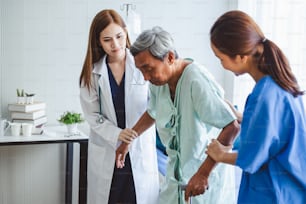 アジアの医師の女性と看護師は、病院のベッドに座っている障害のある老人患者を奨励し、アジアの医療コンセプト