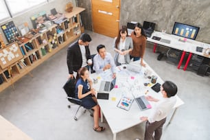 Groupe de gens d’affaires asiatiques et designer créatif se rencontrant dans le bureau, vue de dessus