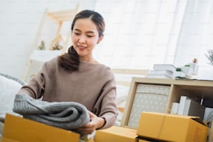 Young asian woman seller packing clothes product for online business, online shopping, shipping box and package