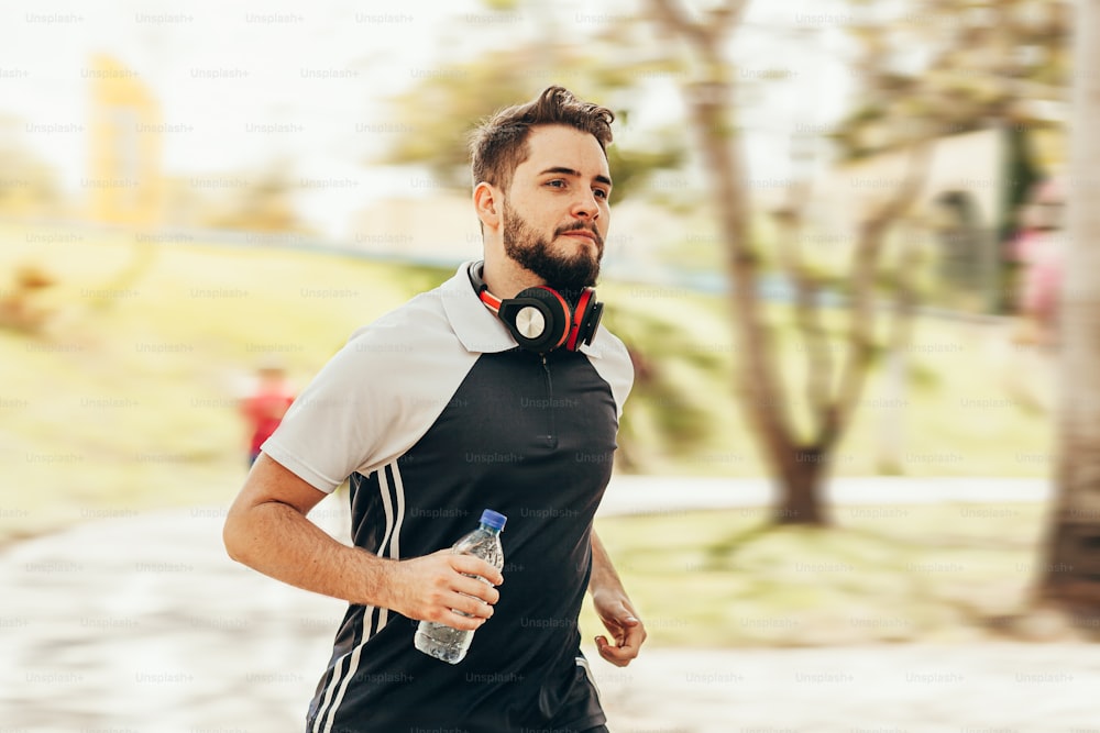 Runner athlete running in park holding water bottle