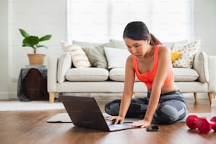 Mujer deportiva que mira y aprende ejercicios de entrenamiento, yoga en línea con entrenador en la pantalla de la computadora portátil en casa