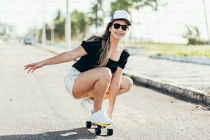 Beautiful young woman with skateboard on the beach