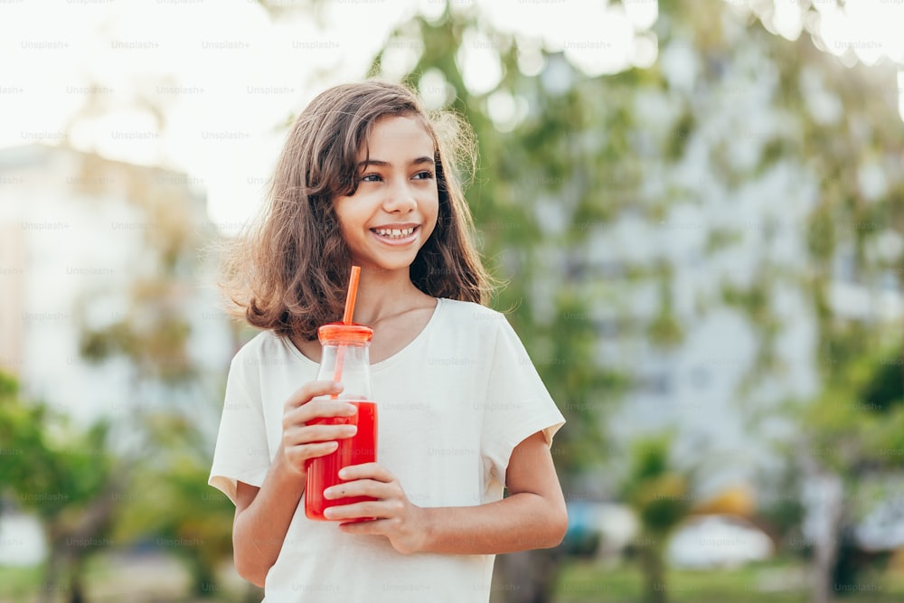 Portrait of young girl drinking juice in the park