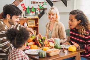 Happy Thanksgiving dinner party with family and food with turkey on table