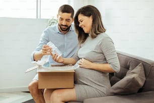 Adult couple expecting baby unpacking baby items purchased online.