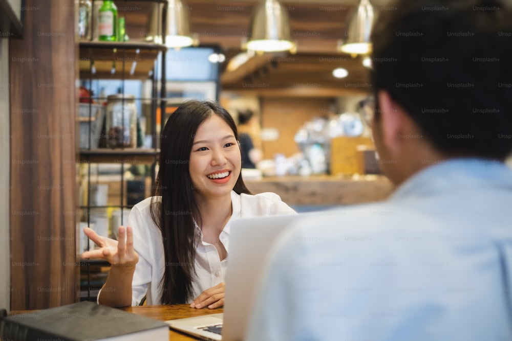 Young beautiful asian business woman in cafe, discussing business during interview with young business man