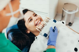 환자의 치아 그늘과 표백 치료를 위한 샘플을 비교하는 치과 의사