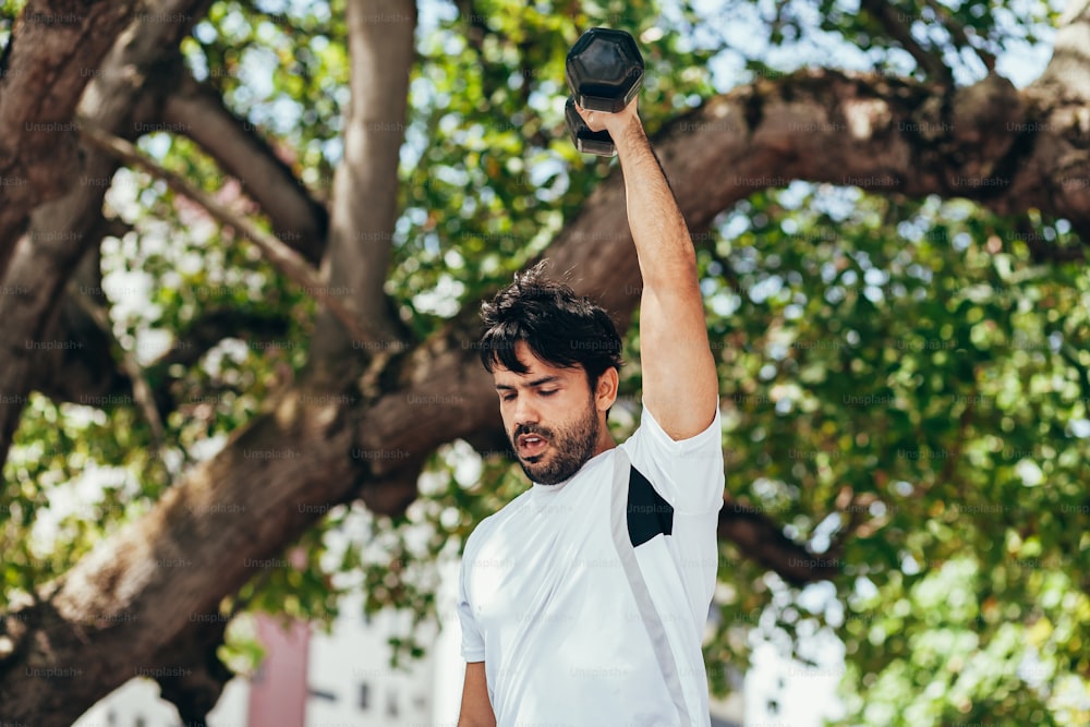 Man training with dumbbell in public park