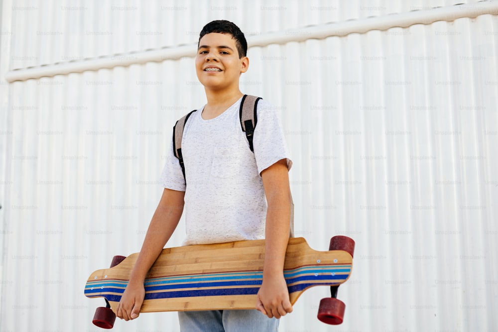 Portrait of teenage boy with skateboard outdoors