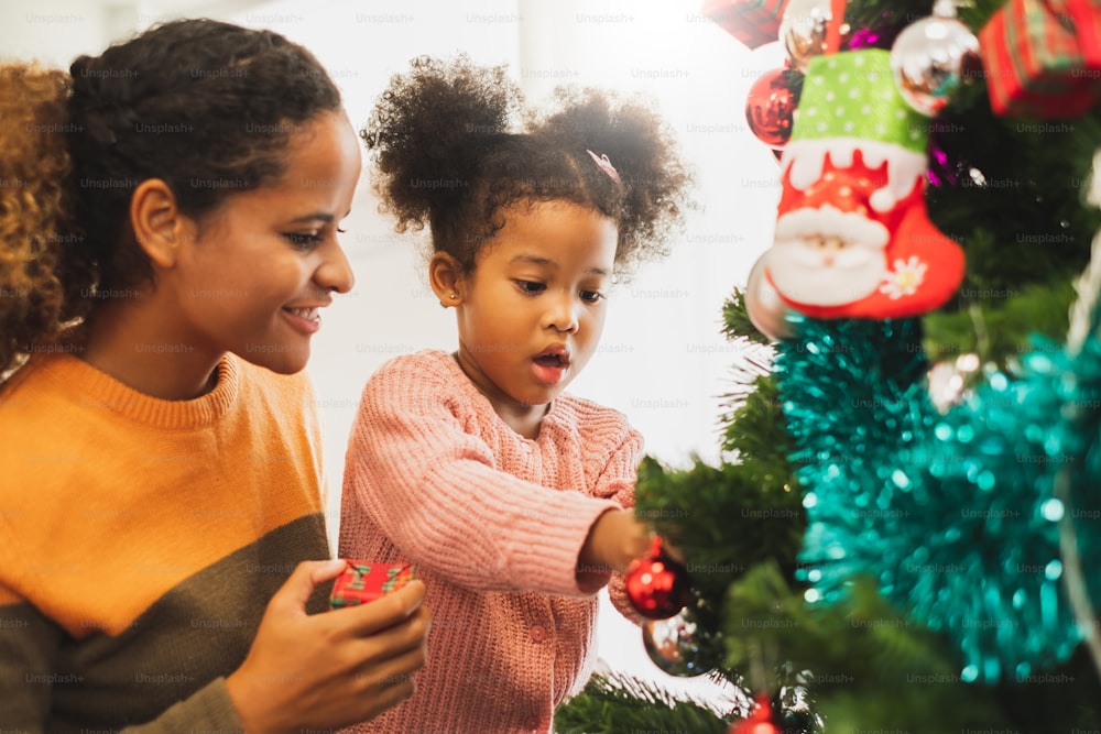 Black african mother and her cute daughter decorating christmas tree for christmas and happy new concept