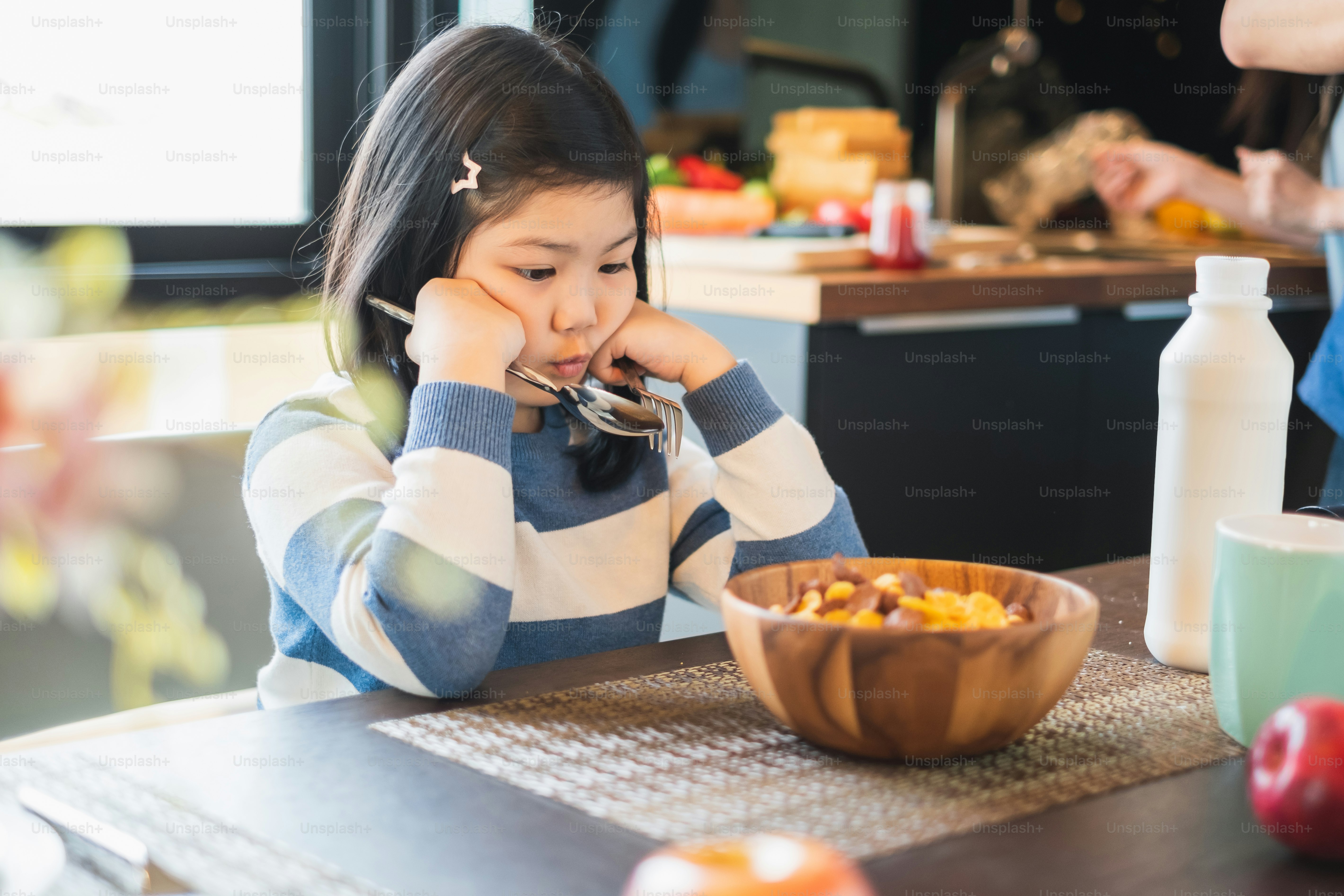 Asian girl kid having breakfast cereal at home kitchen