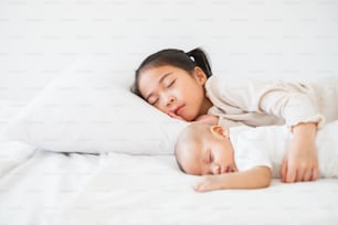 Asian cute girl sleep with baby on white bed