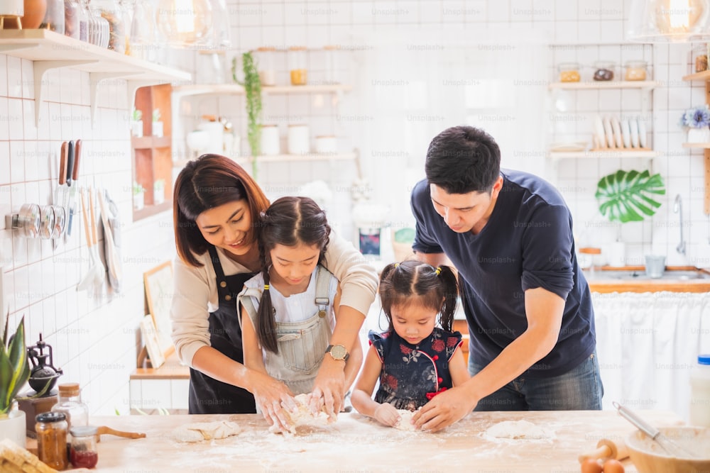 La familia asiática disfruta jugando y cocinando en la cocina de su casa
