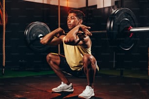 Homme musclé dans un gymnase faisant des exercices de poids lourds. Jeune homme faisant de l’haltérophilie dans un club de santé