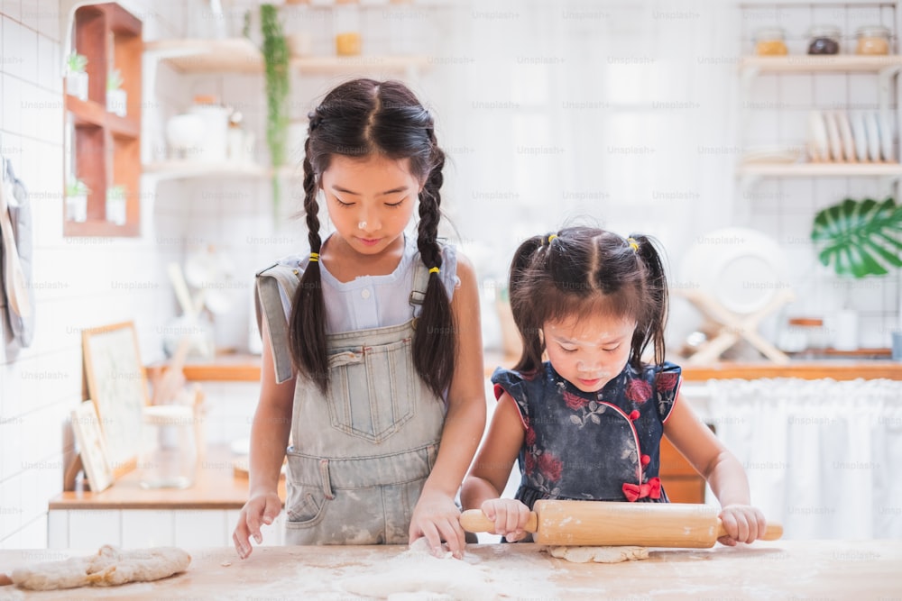Dos chicas lindas haciendo pastel / cocinando en la cocina en casa