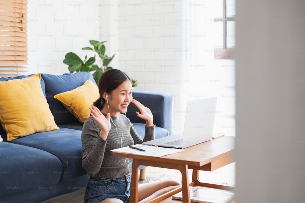 Joven empresaria asiática trabaja en casa y se reúne por videoconferencia virtual con colegas empresarios, trabajo en línea, videollamada debido al distanciamiento social en la oficina en casa