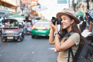 Mujer asiática turista mochilera viajando y tomando fotos en Khao San road, Bangkok, Tailandia