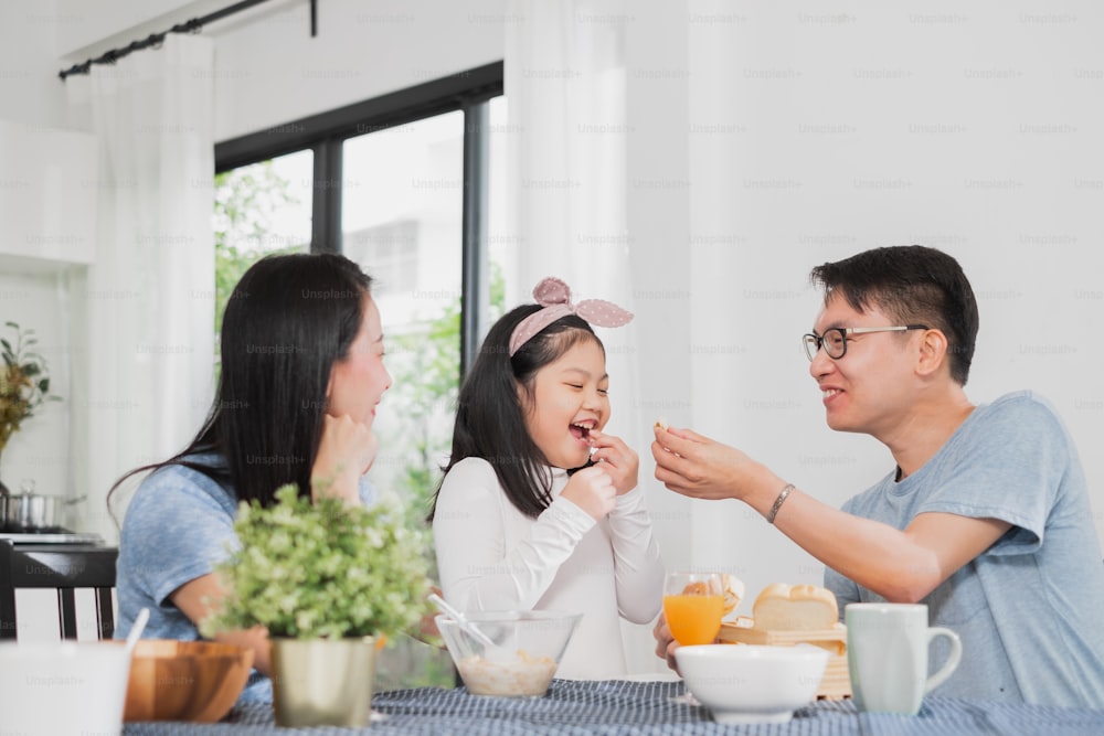 Famille asiatique heureuse de prendre le petit déjeuner sur la table dans la cuisine