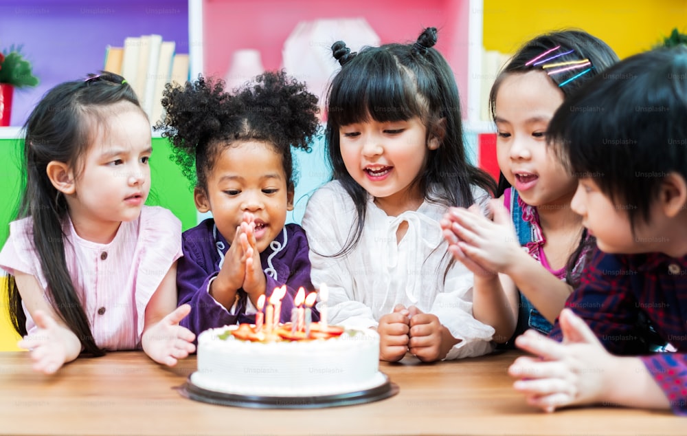 Group diversity kids blowing birth day cake.