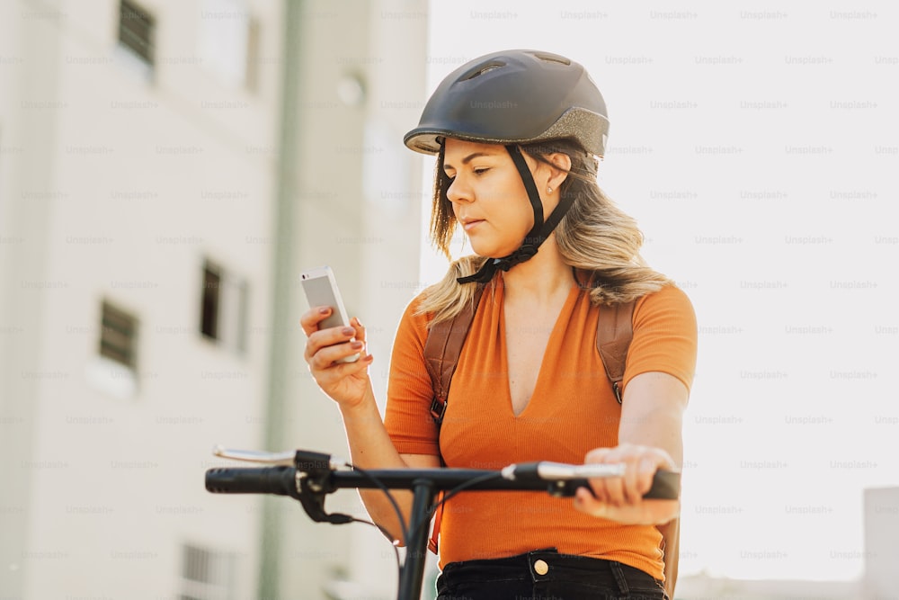 Young woman standing on bicycle using smartphone in the city