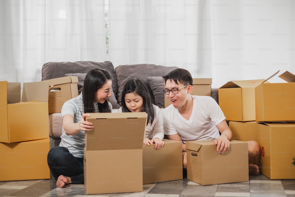 Familia asiática que se muda a un nuevo hogar / casa y desempaca cajas