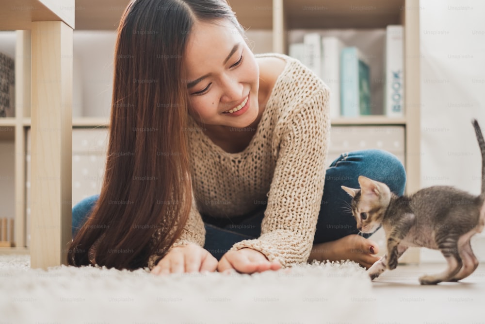 Giovane donna asiatica che tiene e gioca con il suo simpatico gattino gatto con un bel momento, animale domestico e concetto umano