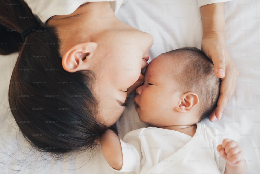 若いアジアの母は幸せを感じて彼女の新生児とキス