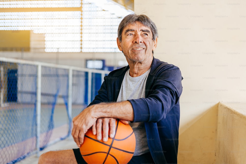Physical activity in old age. Portrait of elderly man playing basketball