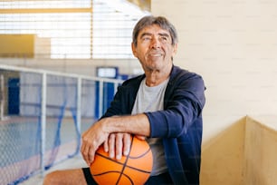 Atividade física na velhice. Retrato do homem idoso que joga o basquete