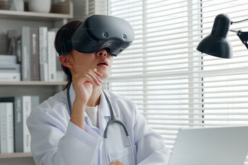 Asian woman doctor using 3d VR virtual reality to analyze medical exam, report in medical office hospital