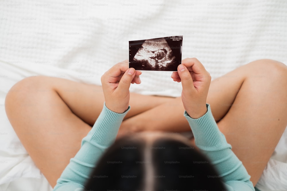 Asian pregnant woman looking to ultrasound image, focus on ultrasound image