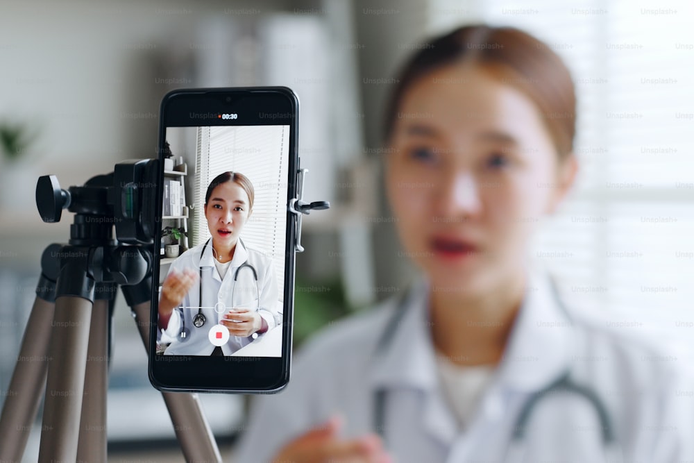 Femme médecin asiatique faisant en ligne diffusion en direct diffusion parler sur l’enregistrement de la caméra dans l’hôpital, blogueur médical et de soins de santé, concept de vlogger