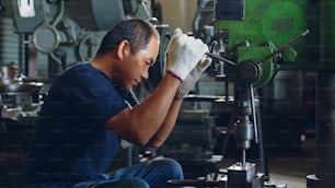 Trabajador técnico que usa una máquina perforadora para trabajar metales en una fábrica de taller