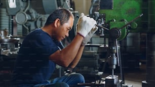 Technician worker using drilling machine for metalworking in workshop factory