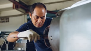 Technician asia worker using vernier caliper measure detail of workpiece for checking size in workshop lathe machine factory