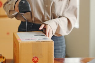 Asian woman working at online store warehouse, using barcode reader check on customer parcel box, online e-commerce retail small business concept