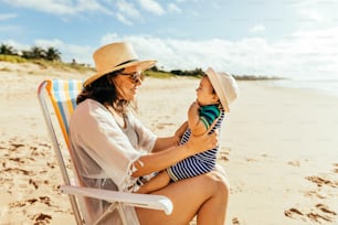 Mãe e seu filho bebê brincando na praia durante as férias de verão