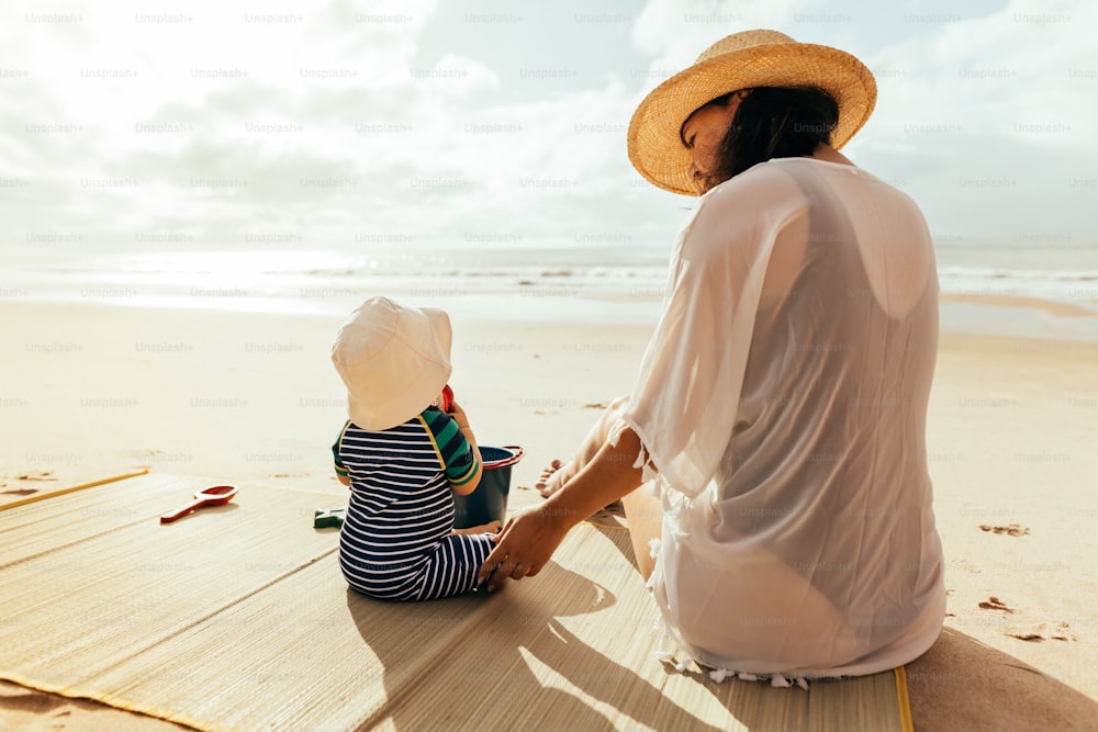 Mother and her baby son playing on the beach during summer vacation