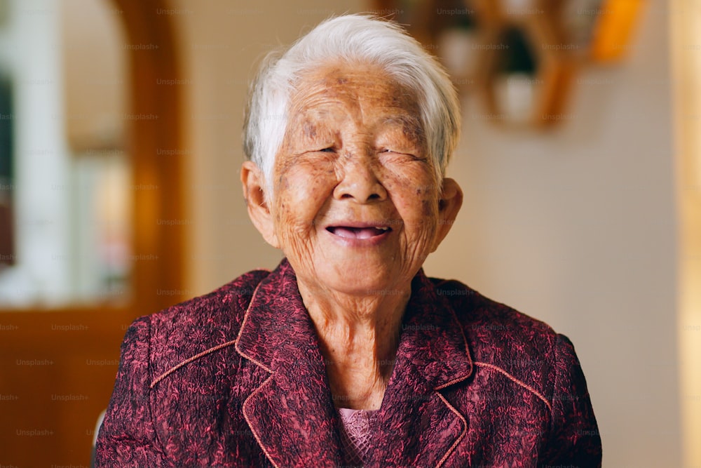 Retrato de mujer asiática mayor feliz mira a la cámara y luego sonríe y ríe