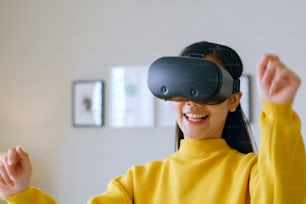 Mulher asiática jovem dançando enquanto usa fone de ouvido VR 360 para realidade virtual / metaverso em casa