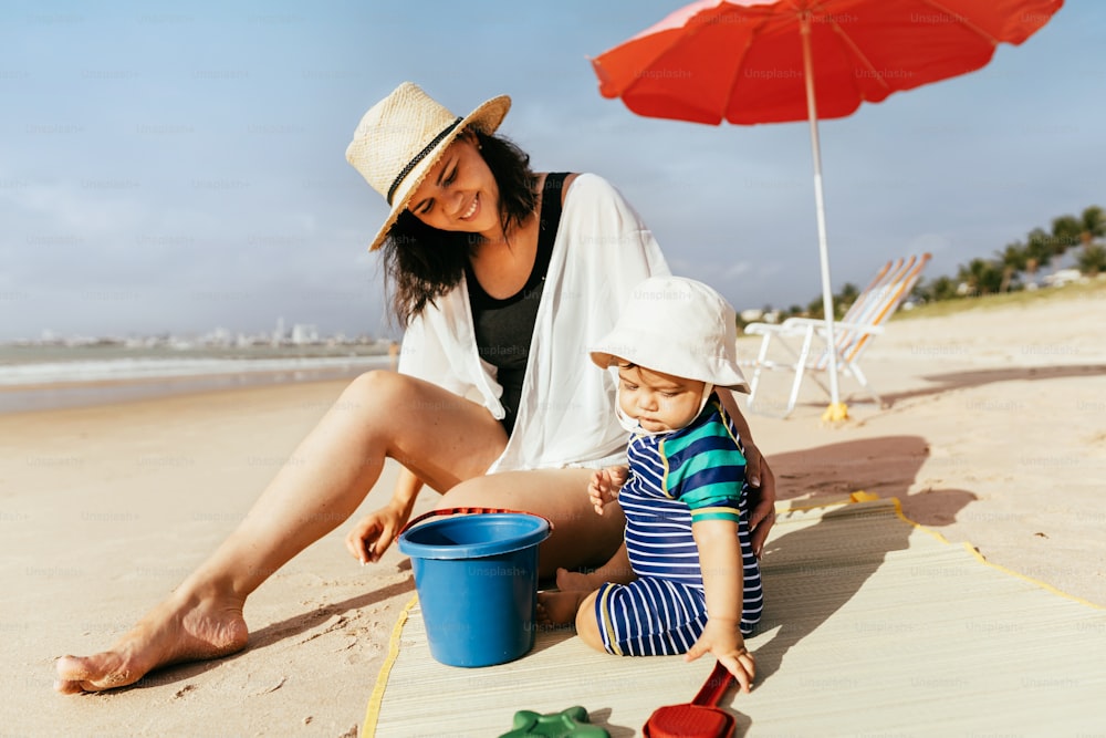 Mãe e seu filho bebê brincando na praia durante as férias de verão