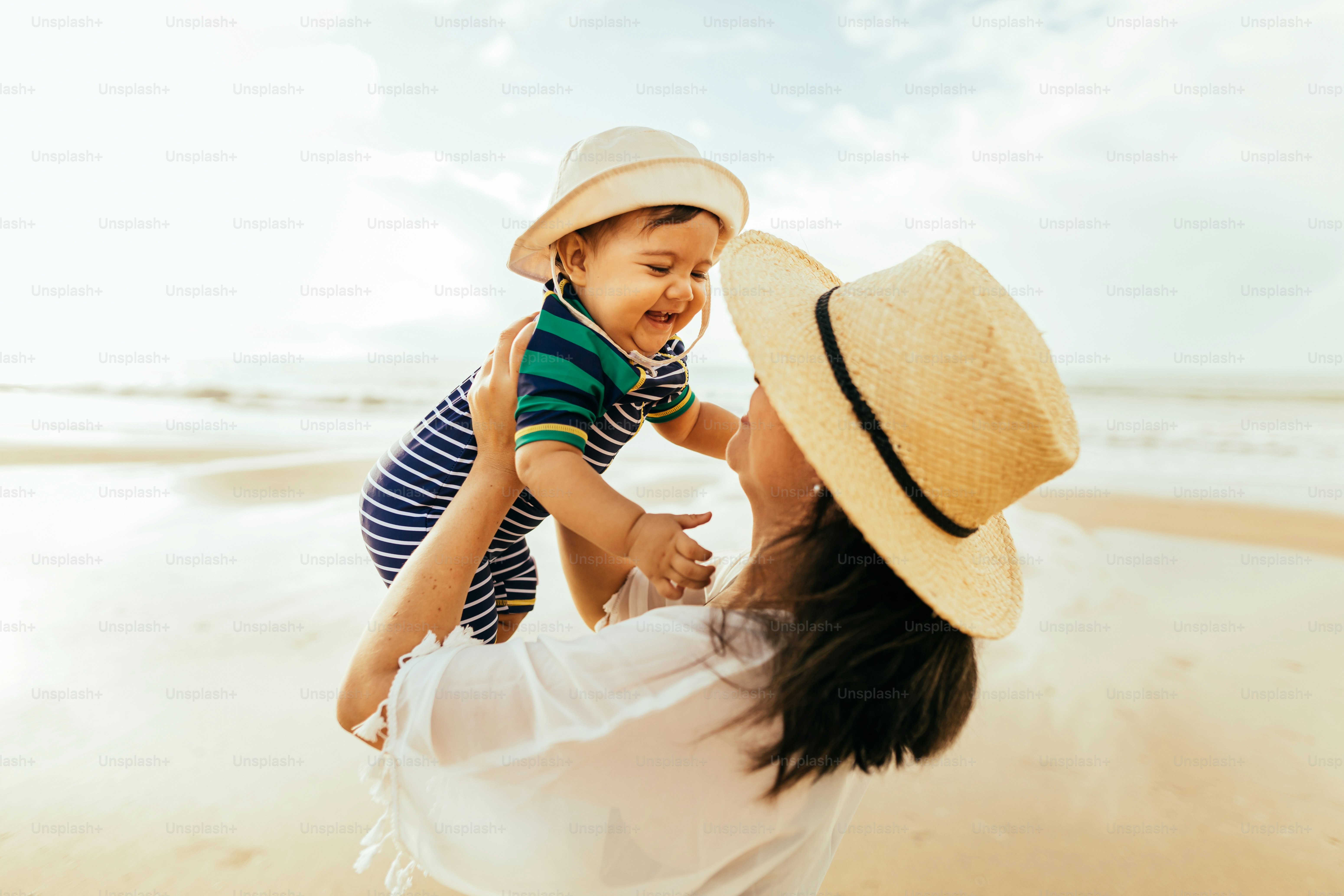Ibu dan bayi laki-lakinya bermain di pantai selama liburan musim panas