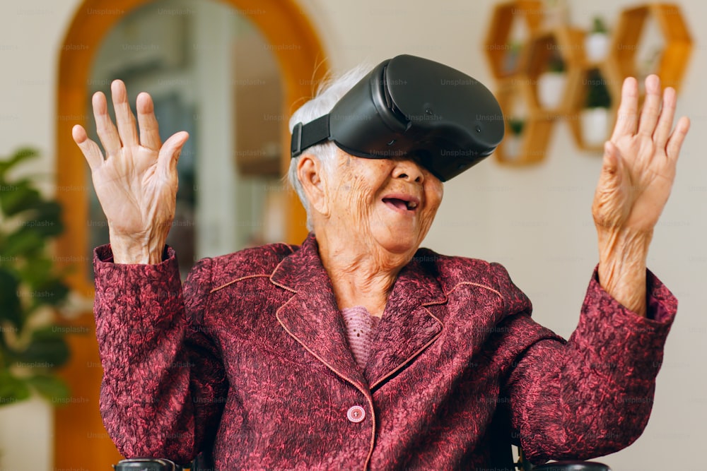 Asian old senior wearing vr headset feeling excited with metaverse. Retirement and senior lifestyle at home