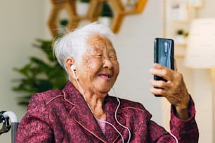 Asiatischer alter Senior macht Videoanruf über Mobiltelefon und spricht mit der Familie
