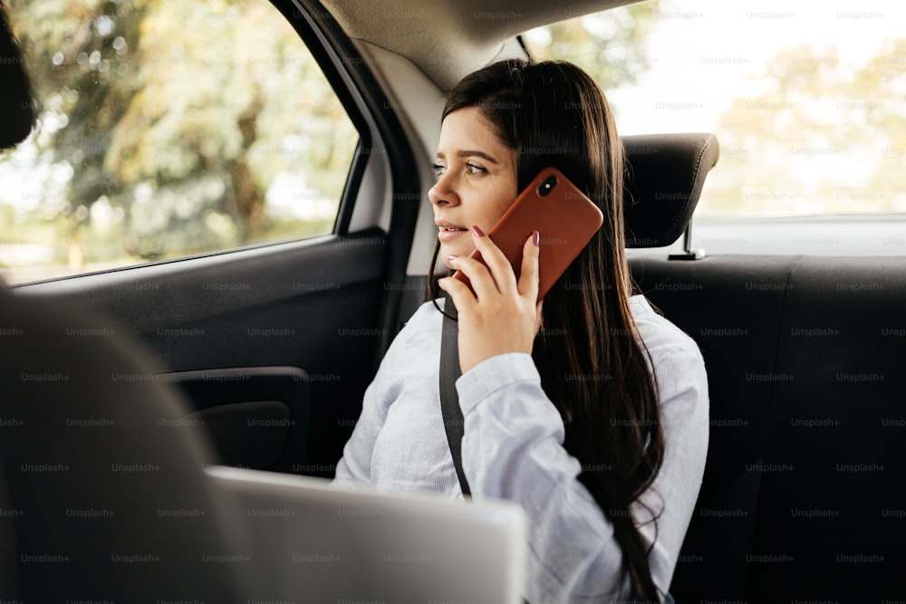 Businesswoman using smartphone and laptop in car