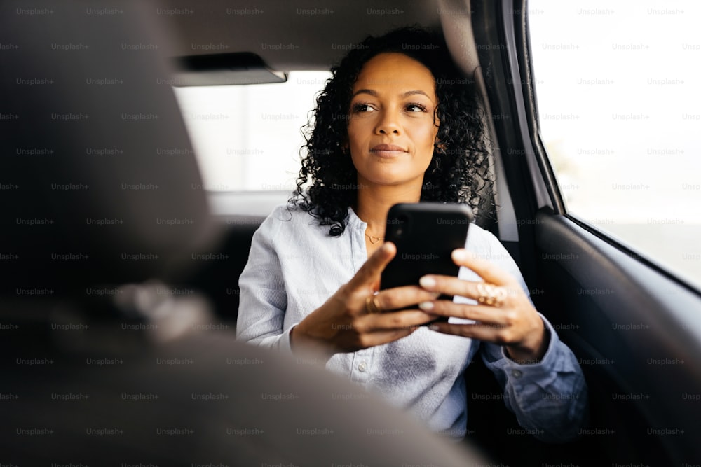 Femme d’affaires utilisant un smartphone dans la voiture