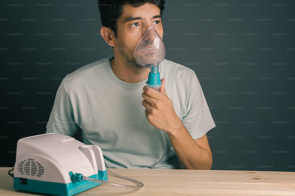 Portrait d’un jeune homme utilisant un inhalateur / nébuliseur