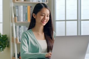 Young Asian woman using laptop computer for online working, studying, learning chatting in social media at home.