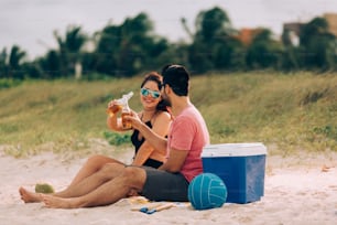 Couple drinking beer and having fun on the beach