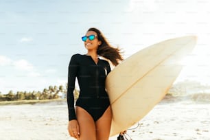 그녀의 서핑 보드를 들고 해변에서 젊은 서퍼 여자의 초상화